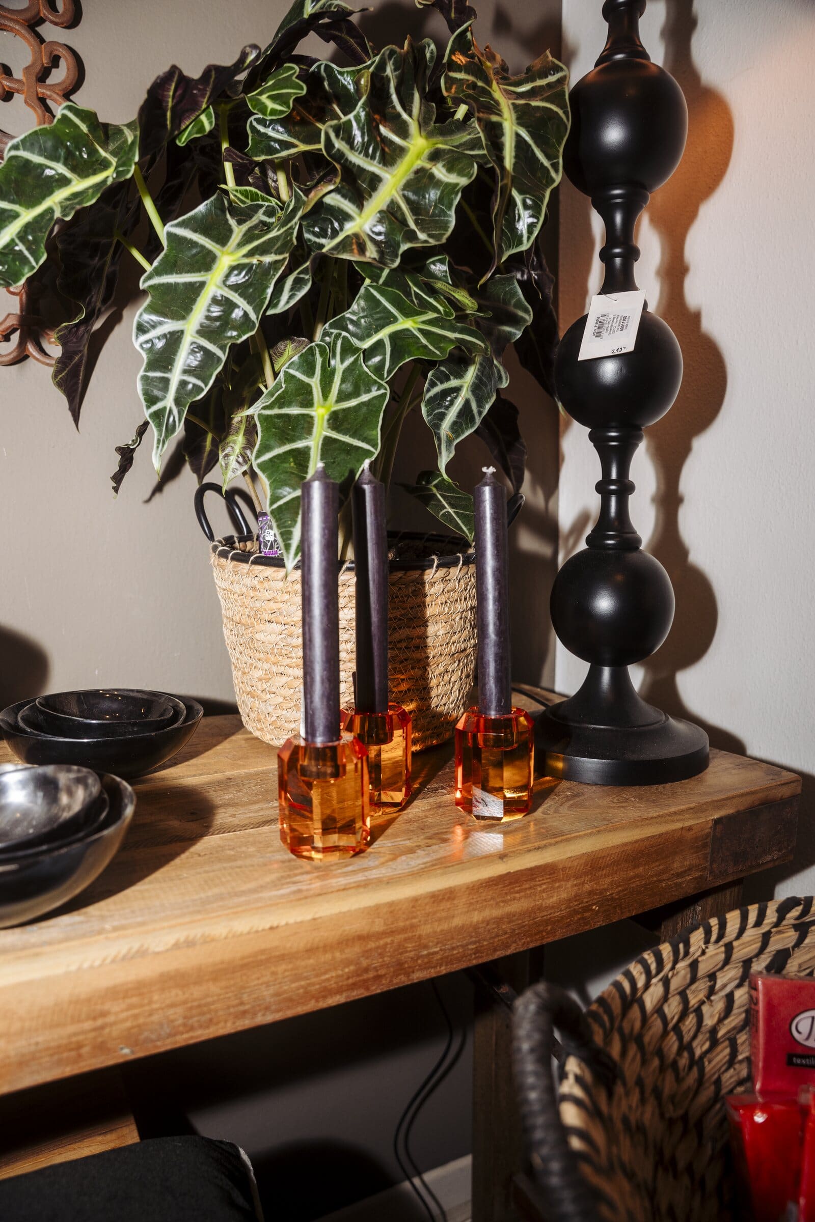 Schwarze Kerzenständer, Kerzenhalter aus Amberglas und eine Grünpflanze auf einem Holztisch